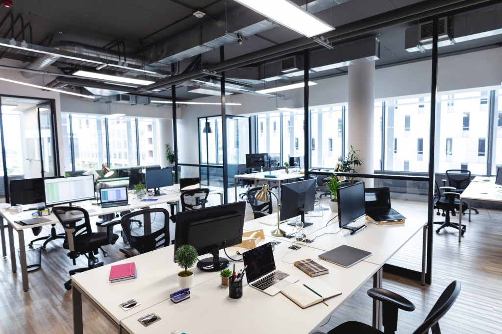 Interior of a large modern office with desks, computers and windows