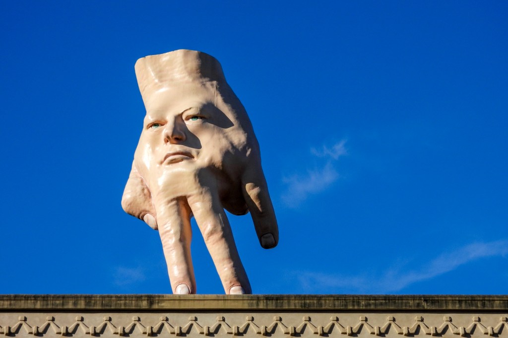 Giant 16-foot sculpture called Quasi tiptoes atop an art gallery roof in Wellington, New Zealand